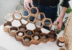 a person standing next to a table holding a wooden box filled with mirrors and bottles