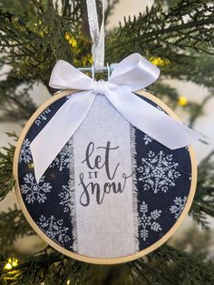 a christmas ornament hanging from a tree with the words let it snow on it