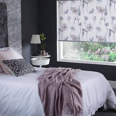 a bedroom with black walls and white bedding has pink flowers on the window sill