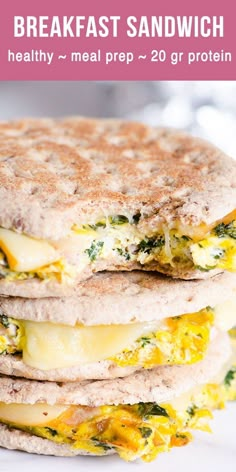 a stack of breakfast sandwiches with cheese and spinach on top, sitting on a white plate