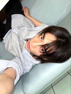 a woman laying on top of a blue couch next to a computer keyboard and mouse