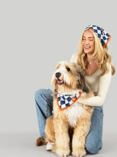 a woman sitting on the floor with her dog wearing a bandana and smiling at the camera