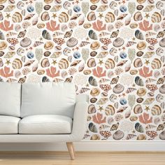 a white couch sitting in front of a wall with shells on it