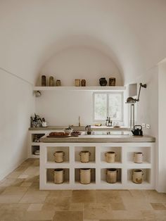 a white kitchen with lots of pots and pans on the counter