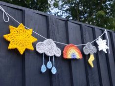 crocheted stars and clouds are hung on a line next to a wooden fence