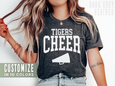 This personalized cheer shirt is the perfect tee to rep your school or cheerleader! Our Bella+Canvas tees have that light and vintage feel. ♥ 》 》HOW TO ORDER 《 《 * Select size + color from the drop down menus * Type your custom mascot in the personalization box. * Add to cart + place order ♥ * Your shirt is now in production & will be ready to ship in 1-3 days! 》 》SIZING 《 《 These are soft men's-cut shirts. Although these are unisex, I would NOT downsize. Check out the fit guide in the images. Customizable Casual T-shirt For Cheerleading, Cheerleading Graphic Print Team-colored Tops, Team-colored Crew Neck T-shirt For Cheerleading, Team-colored Tops With Graphic Print For Cheerleading, Team-colored Varsity Tops For School, Team-colored Varsity School Tops, Varsity Style Team-colored School Top, Team-colored Tops For School Sports Season, Team-colored Top For School Sports Season