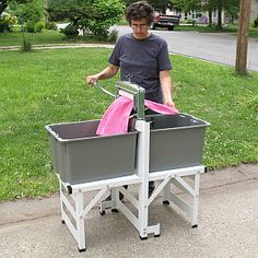 a man pushing a cart with two bins on it in front of the grass