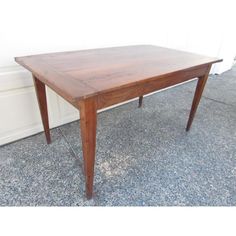 a wooden table sitting on top of a floor next to a white wall and door