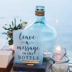 a bottle with leave a message in it sitting on a table next to some candles