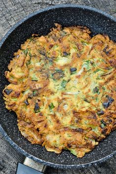 an omelet is sitting in a skillet on the wooden table next to some utensils