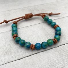 Rustic brown leather and blue-green Azurite beaded bracelet. The stabilized Azurite stones have beautiful blue and green colors. These bracelets look great alone or stacked together and with other bracelets. The classic look of gemstones with modern and edgy leather. Groups of three gemstones knotted together around a leather bracelet. Finished with a sliding knot clasp. The clasp adjusts to help you get the perfect fit. Slide the leather knot over the bracelet straps to open up the bracelet. Sl Adjustable Earthy Blue Beaded Bracelets, Adjustable Blue Beaded Earthy Bracelet, Adjustable Turquoise Beaded Chrysocolla Bracelet, Adjustable Turquoise Chrysocolla Beaded Bracelet, Rustic Blue Adjustable Beaded Bracelets, Rustic Adjustable Blue Beaded Bracelet, Rustic Blue Adjustable Beaded Bracelet, Rustic Adjustable Blue Bracelets, Rustic Blue Adjustable Bracelets