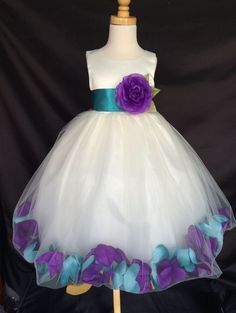 a white dress with purple and blue flowers on the waist, sitting on a mannequin