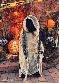 a person in a ghost costume standing on a brick walkway with halloween decorations behind him