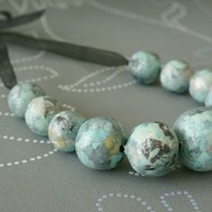 a close up of a bead necklace on a table with a ribbon around it