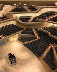 an empty auditorium with rows of seats and a piano on the floor in front of it