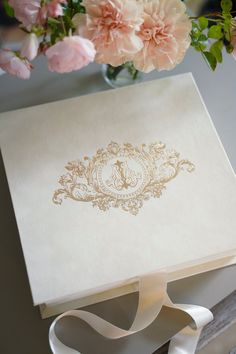 a bouquet of flowers sitting on top of a table next to a white box with a ribbon