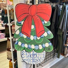 a sign with a red bow on it is hanging in front of a clothing rack