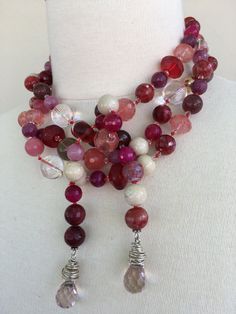 Pink Jade Lariat, hand-knotted in red silk, faceted cherry quartz, smoky quartz, fossil stone, faceted quartz, agate, African antique glass, 8 mm. 14 k gold filled ball, 3mm Swarovski crystal. Weight is 7. 7oz. with sterling silver findings and toggle. This one of necklace is 64 inches in length, weight is 8.8 oz, hand-crafted in North Palm Beach, Florida by designer/artist Christine Smith Elegant Hand Knotted Lariat Jewelry, Elegant Long Agate Necklace, Hand Knotted Pearls, Lariat Necklace Silver, Pearl Lariat Necklace, Pearl Lariat, Hand Knotted Necklace, Pink Jade, Cherry Quartz