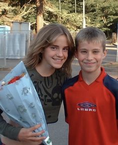 two young people standing next to each other holding flowers