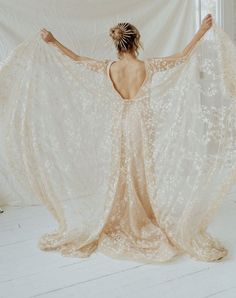 a woman with her back to the camera, wearing a white dress and holding an intricately designed shawl