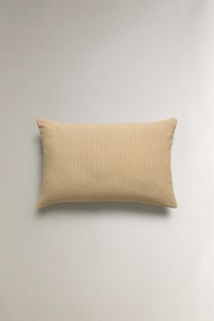 a beige pillow sitting on top of a white wall