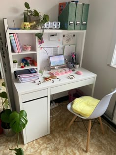 a white desk with a laptop computer on top of it next to a chair and bookshelf