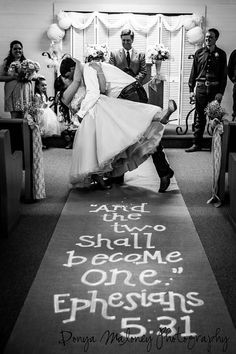 a bride and groom kissing in front of an aisle with words written on the carpet