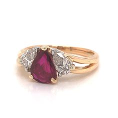 a three stone ring with two pear shaped diamonds on the sides and an oval cut garnet