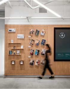 a person walking past a wall with books on it