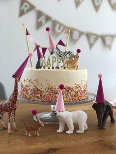 a birthday cake with animal figurines and decorations on the table next to it