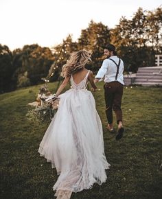 a bride and groom running through the grass