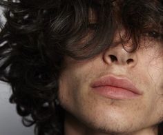 a close up of a person with curly hair and no shirt looking at the camera