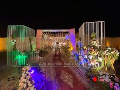 an outdoor wedding venue decorated with flowers and greenery, lit up by colorful lights