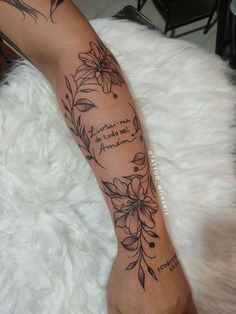 a woman's arm with flowers and words on it