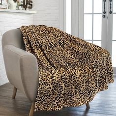 a leopard print blanket sitting on top of a chair next to a white brick wall