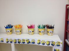 three buckets filled with colored pencils sitting on top of a white table next to a book shelf