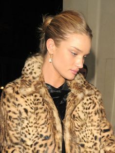 a woman in a leopard print coat looking at her cell phone