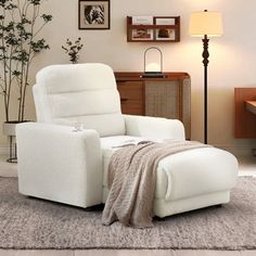 a white recliner chair sitting on top of a rug in a living room next to a lamp