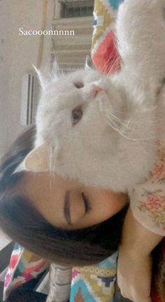 a woman laying on top of a bed next to a white stuffed animal cat with her eyes closed