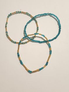 The bracelets are about 7 inches long and made with glass seed beads and stretchy string. Turquoise Beaded Bracelets With Gold Beads As Gift, Adjustable Turquoise Stretch Bracelet With Tiny Beads, Blue Heishi Beads Bracelet With Gold Accents, Blue Heishi Beads Bracelet With Gold Beads, Turquoise Stretch Bracelet With Tiny Beads For Beach, Adjustable Turquoise Beaded Bracelet With Gold Beads, Turquoise Heishi Beads Bracelet With Tiny Beads, Turquoise Beaded Bracelets With Gold Beads, Turquoise Beaded Bracelets With Gold Accents