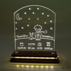 an illuminated night light with a cat and moon on the top, in front of a gray background