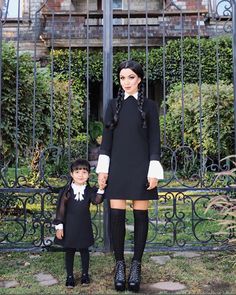 a woman and child standing in front of an iron gate