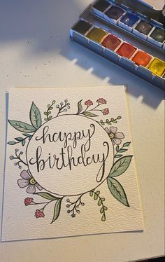 a happy birthday card sitting on top of a table next to some watercolor paints