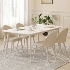 a dining room table with four chairs and a rug on the floor in front of it