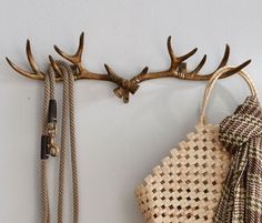 a deer antlers head mounted to the side of a wall next to a woven bag