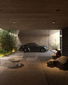 a car is parked in the garage next to a chair and table with two chairs on it