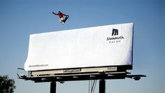 a man flying through the air while riding a snowboard on top of a billboard