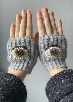 a woman's hands with knitted mittens and eyeballs on them