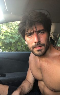 a shirtless man sitting in the back seat of a car