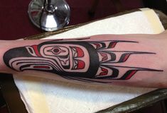 a tattoo on the arm of a person with a totem pole in his hand